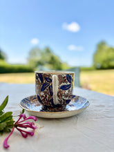 Load image into Gallery viewer, A large cup and saucer with botanical decoration
