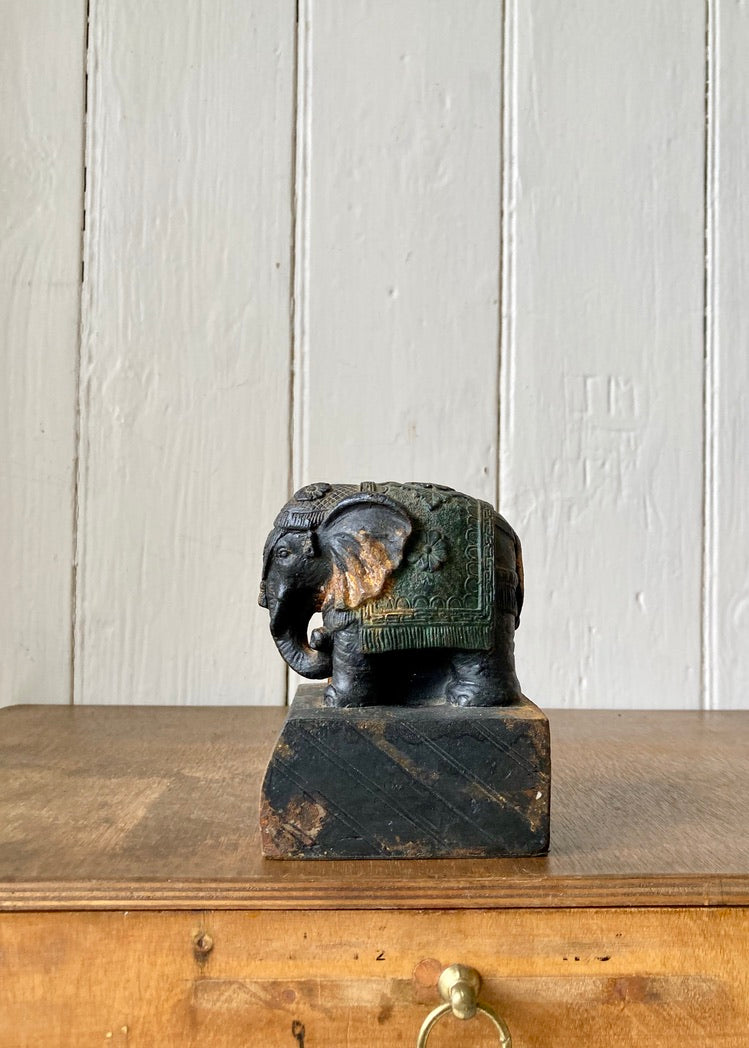 A cast metal elephant on rustic plinth