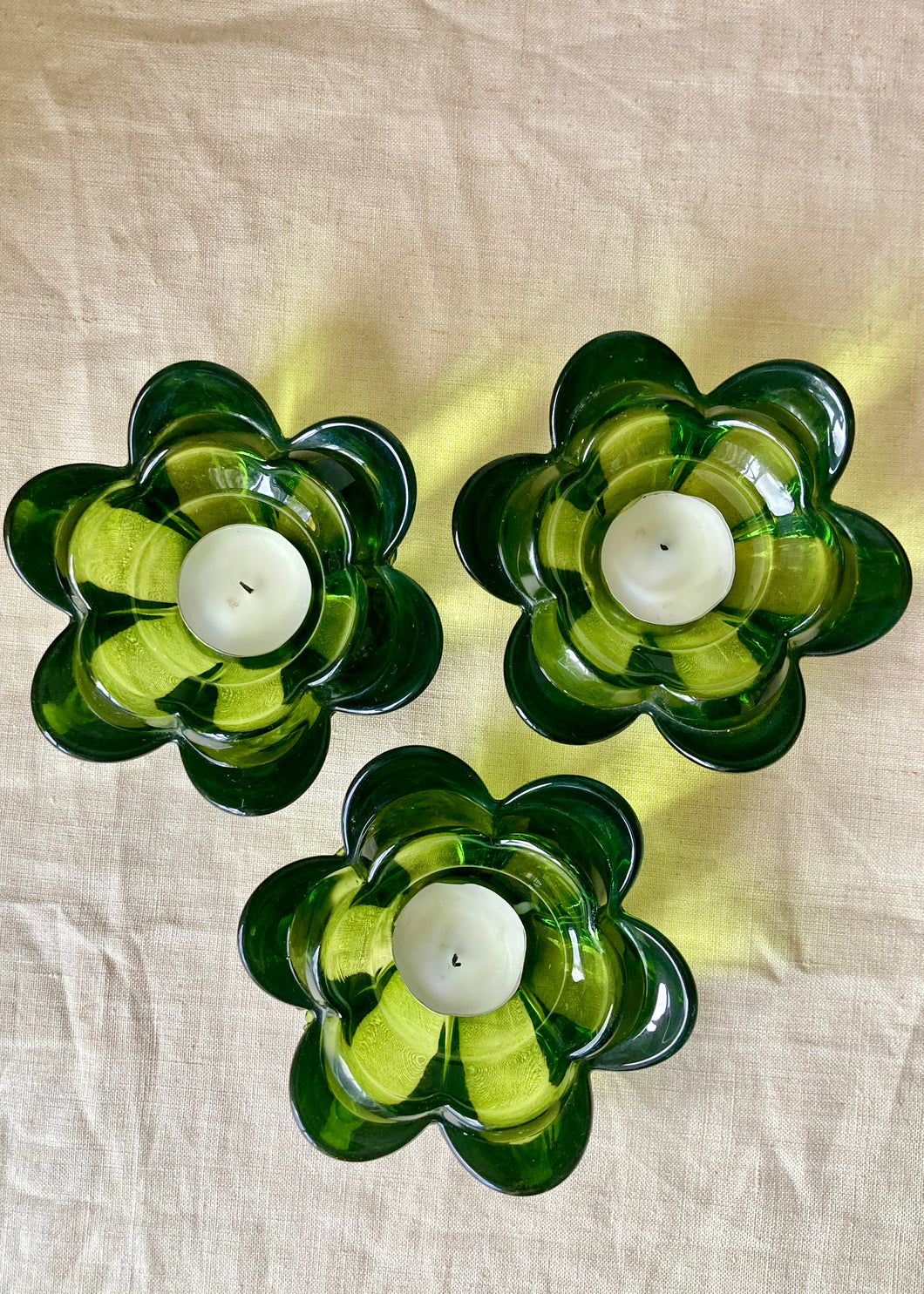 A set of 3 green glass flower tea light holders