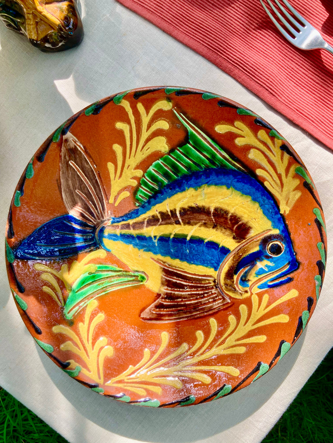 Shallow terracotta dish with vibrant fish hand decoration