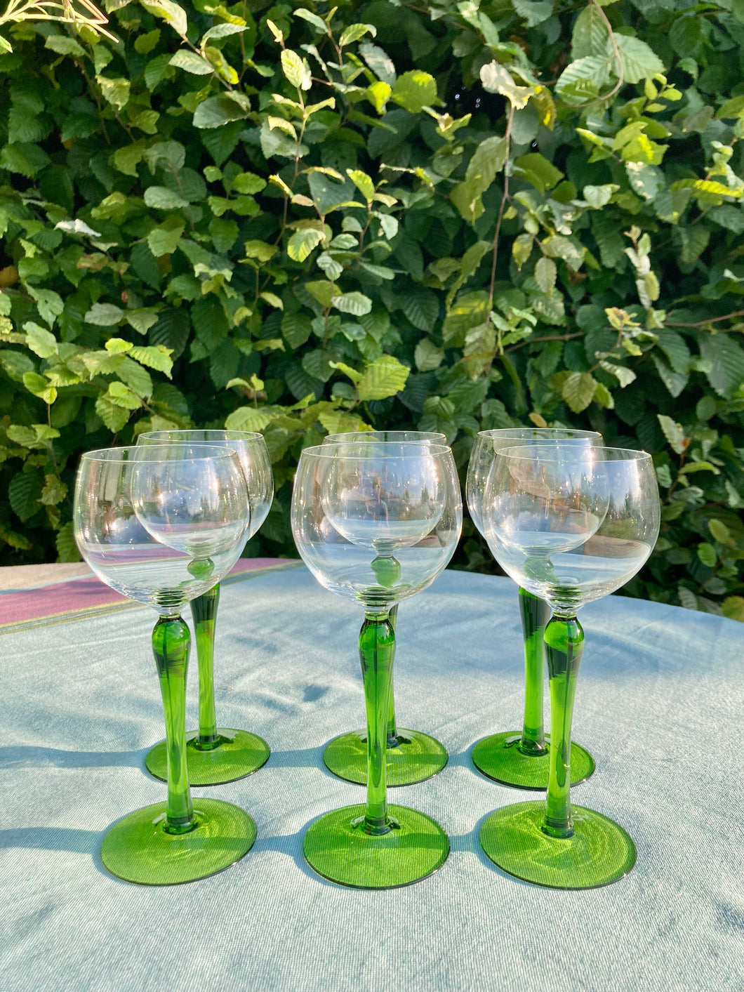 A set of six tall green stemmed wine glasses