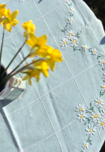 Load image into Gallery viewer, Powder blue tablecloth with embroidered daisies
